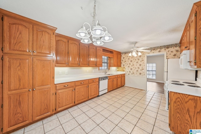 kitchen featuring ceiling fan with notable chandelier, a textured ceiling, white appliances, a healthy amount of sunlight, and sink