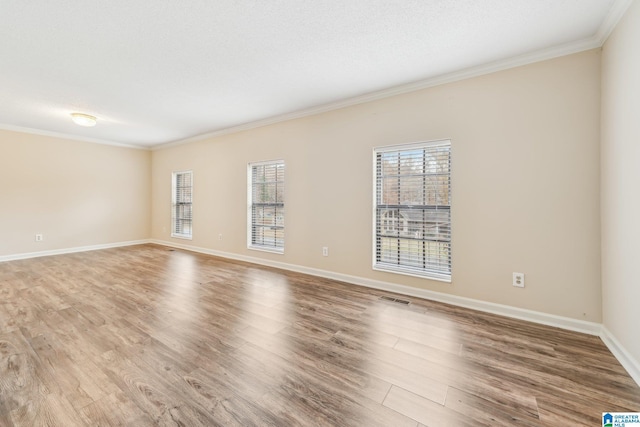 empty room featuring wood-type flooring and crown molding