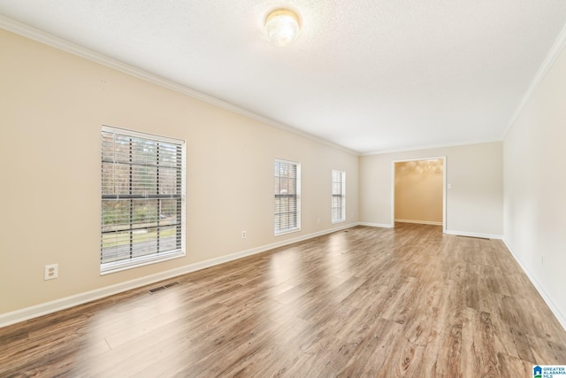 spare room with crown molding, wood-type flooring, and a textured ceiling