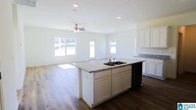 kitchen with white cabinets, wood-type flooring, sink, and an island with sink