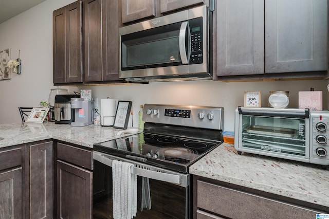 kitchen featuring appliances with stainless steel finishes, dark brown cabinetry, and light stone counters