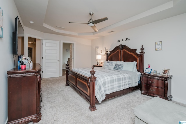 carpeted bedroom featuring a tray ceiling and ceiling fan