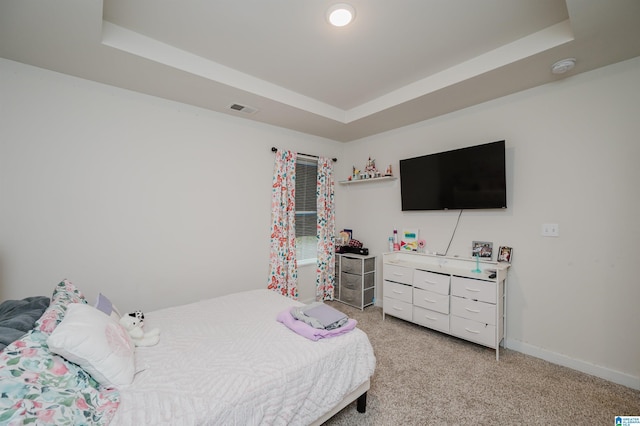 carpeted bedroom featuring a raised ceiling