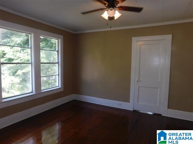 unfurnished room featuring ceiling fan, crown molding, and dark wood-type flooring