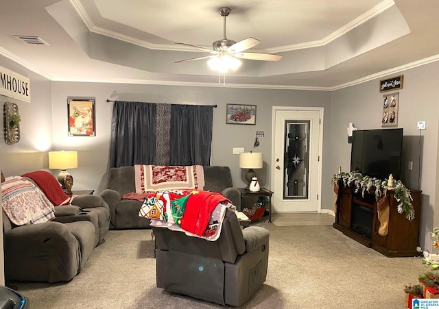 carpeted living room with a tray ceiling, ceiling fan, and ornamental molding