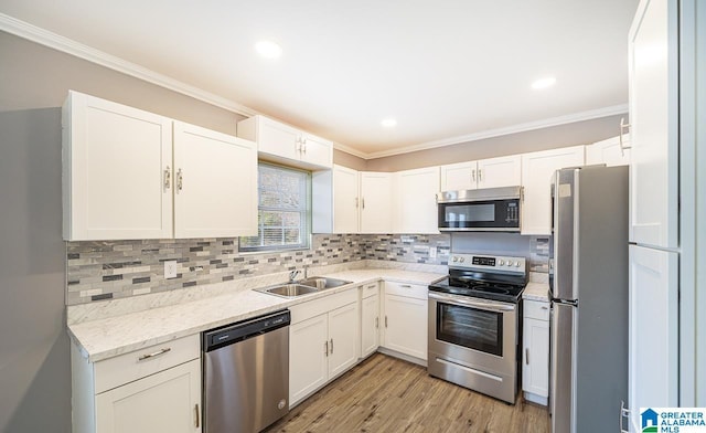 kitchen featuring stainless steel appliances, white cabinetry, ornamental molding, and sink