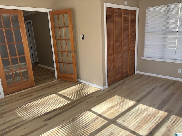 unfurnished bedroom with a closet, wood-type flooring, and french doors