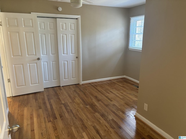 unfurnished bedroom featuring ceiling fan, dark wood-type flooring, and a closet