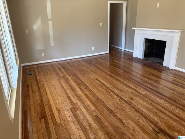 unfurnished living room with hardwood / wood-style floors and a brick fireplace