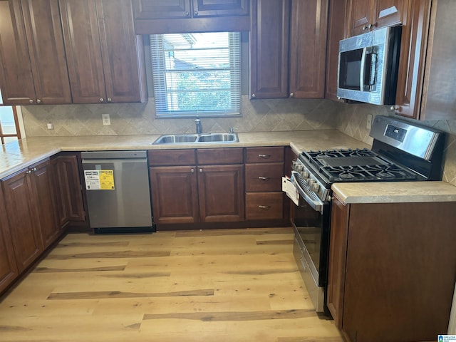 kitchen featuring decorative backsplash, sink, stainless steel appliances, and light hardwood / wood-style floors