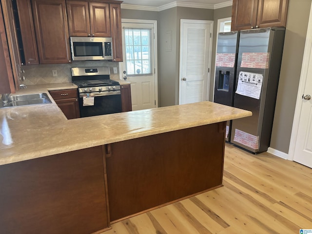 kitchen featuring appliances with stainless steel finishes, backsplash, crown molding, sink, and light hardwood / wood-style floors