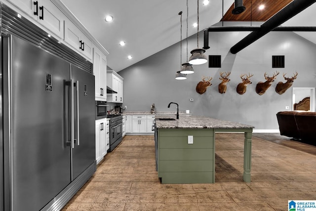 kitchen with light stone counters, a kitchen island with sink, decorative light fixtures, high quality appliances, and white cabinets