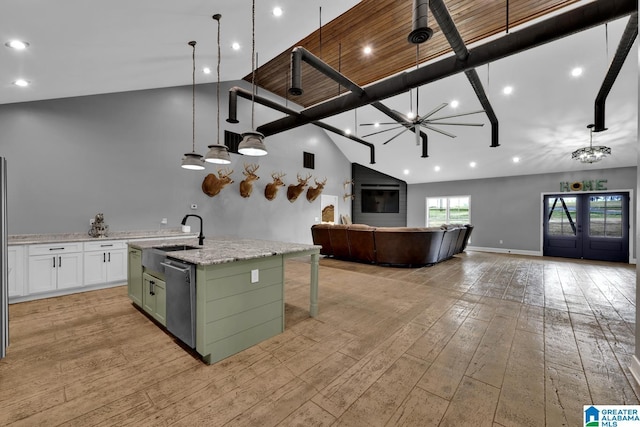 kitchen featuring light hardwood / wood-style flooring, stainless steel dishwasher, an island with sink, pendant lighting, and white cabinets