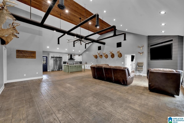 unfurnished living room featuring ceiling fan, wood-type flooring, and a high ceiling