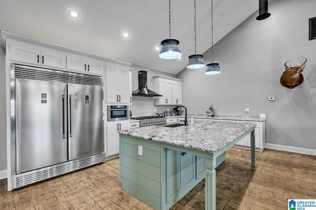 kitchen with white cabinetry, sink, wall chimney exhaust hood, an island with sink, and appliances with stainless steel finishes