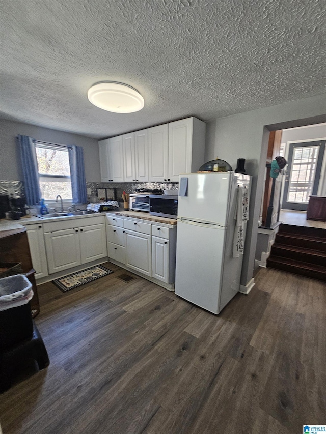 kitchen with sink, dark hardwood / wood-style floors, tasteful backsplash, white fridge, and white cabinetry