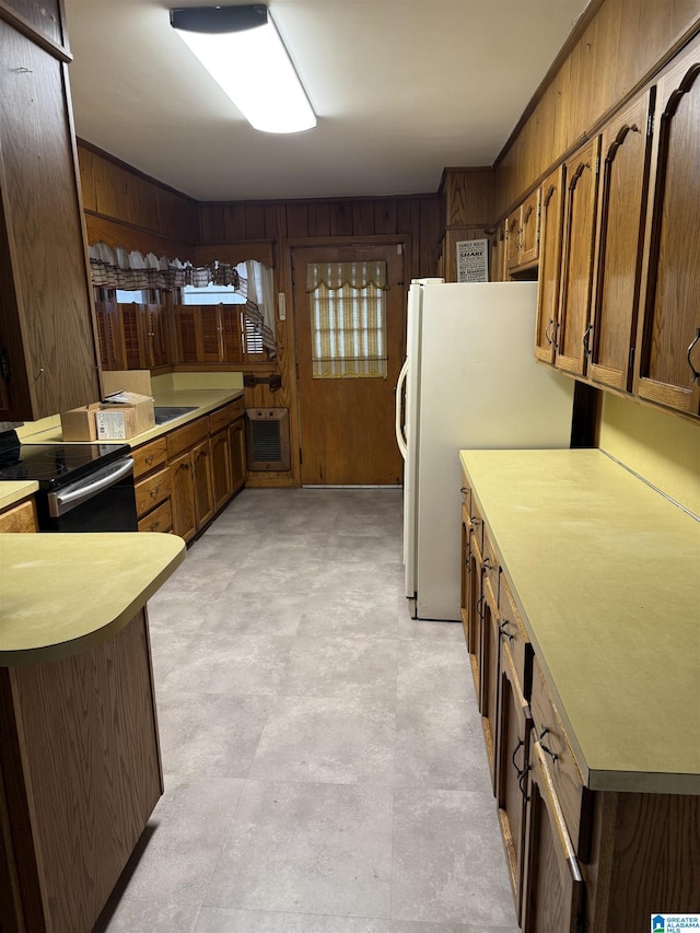 kitchen featuring stainless steel electric range, wood walls, white fridge, kitchen peninsula, and heating unit