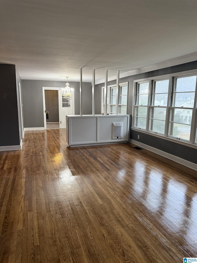 unfurnished living room with a wall mounted air conditioner, a notable chandelier, and dark hardwood / wood-style floors