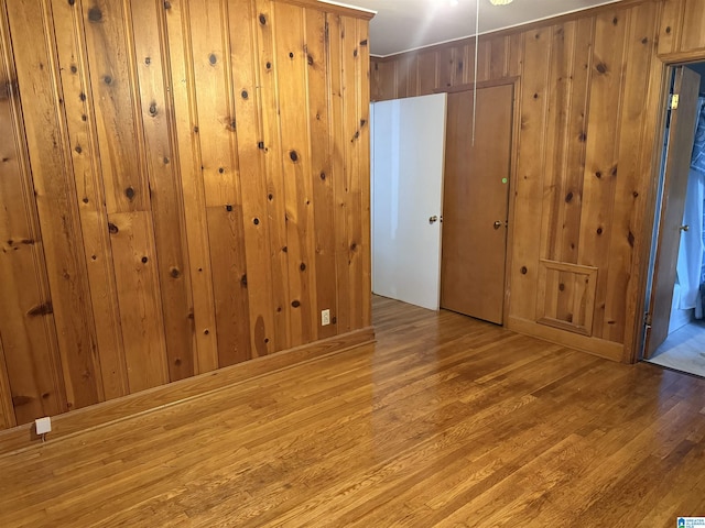 empty room featuring wooden walls and light hardwood / wood-style flooring