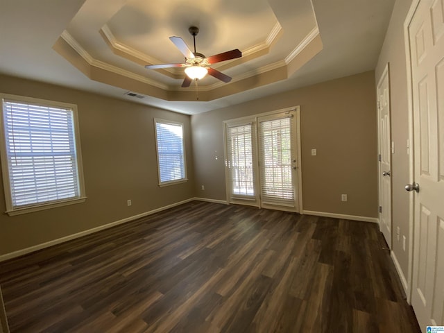 spare room featuring ceiling fan, a raised ceiling, dark wood-type flooring, and a wealth of natural light