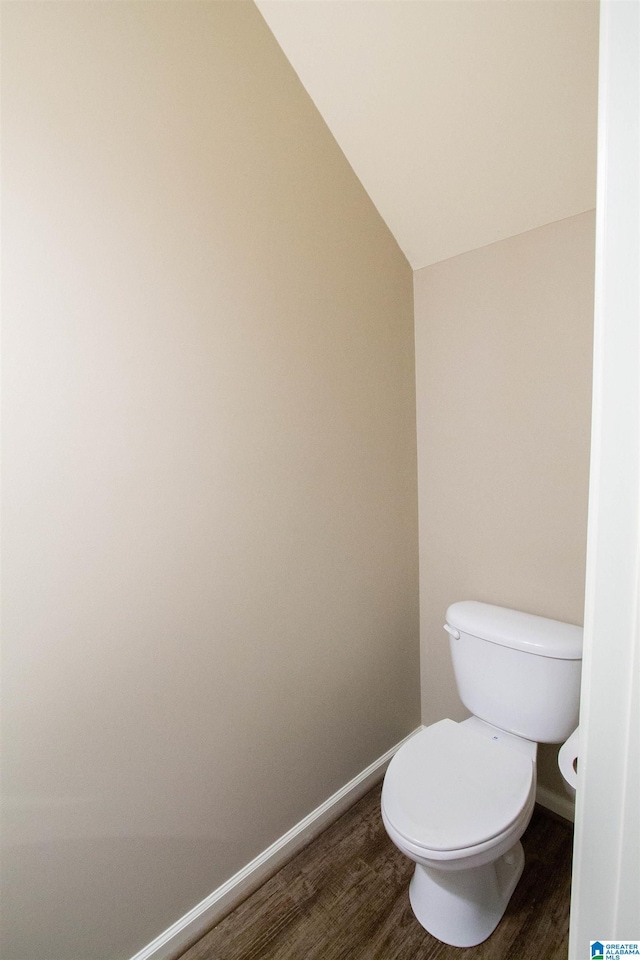 bathroom featuring hardwood / wood-style flooring, toilet, and vaulted ceiling