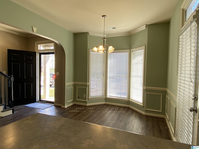 foyer with ornamental molding, dark hardwood / wood-style flooring, an inviting chandelier, and a healthy amount of sunlight