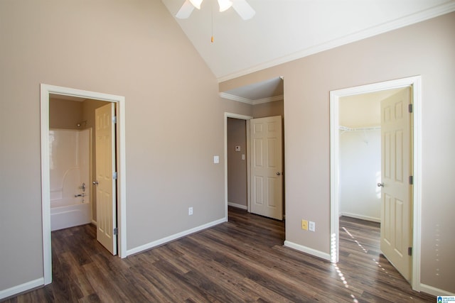 unfurnished bedroom with lofted ceiling, dark wood-type flooring, a walk in closet, ceiling fan, and ornamental molding