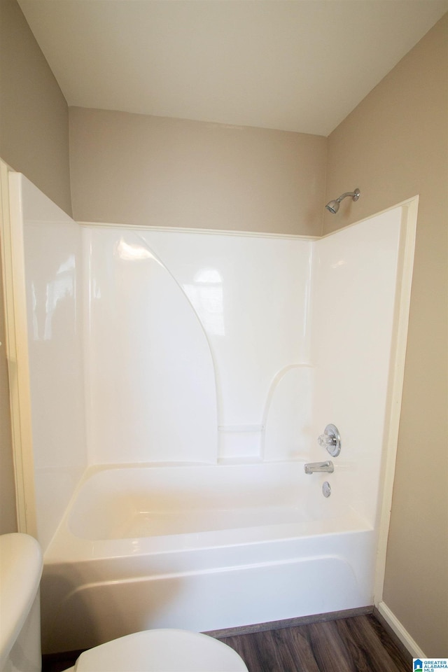 bathroom featuring hardwood / wood-style floors, shower / bathtub combination, and toilet