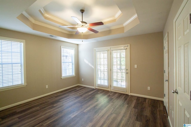 unfurnished room with a tray ceiling, ceiling fan, dark hardwood / wood-style floors, and ornamental molding