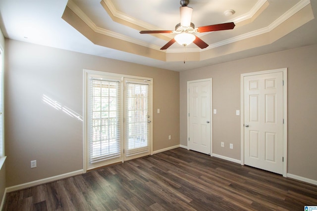 unfurnished room featuring a tray ceiling, ceiling fan, ornamental molding, and dark hardwood / wood-style floors