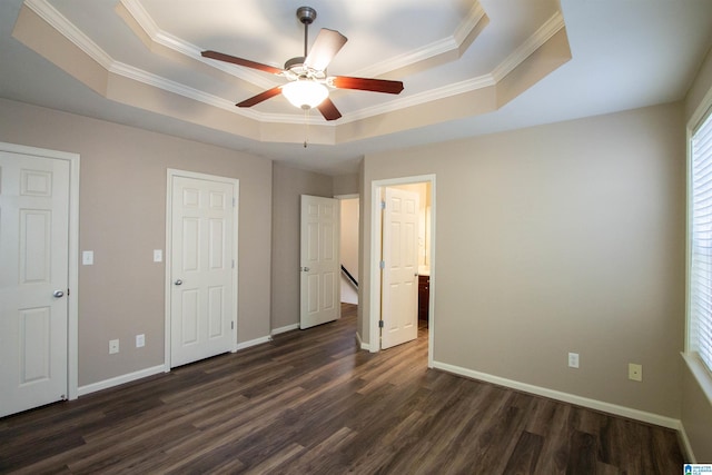 unfurnished bedroom featuring a tray ceiling, ceiling fan, crown molding, and dark hardwood / wood-style floors