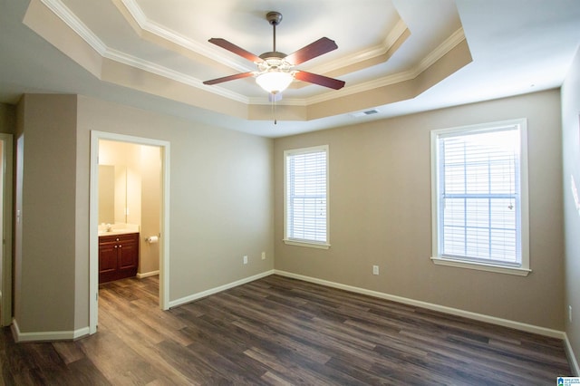 unfurnished bedroom featuring a tray ceiling, ceiling fan, crown molding, and dark wood-type flooring