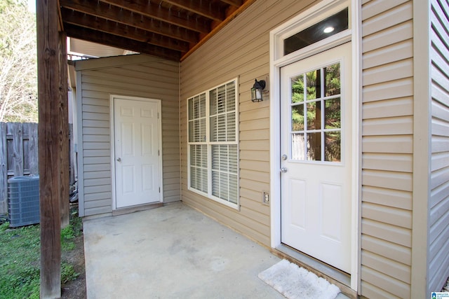 view of exterior entry with a patio and central AC unit