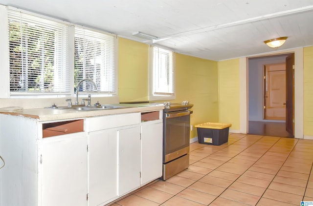 kitchen featuring white cabinets, light tile patterned floors, and sink