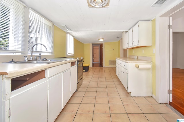 kitchen with light tile patterned floors, white cabinetry, and sink