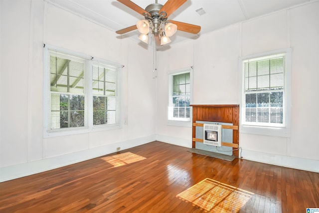 unfurnished living room featuring wood-type flooring, heating unit, and ceiling fan