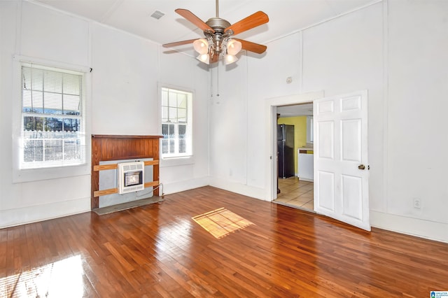 unfurnished living room featuring hardwood / wood-style flooring, plenty of natural light, ceiling fan, and heating unit