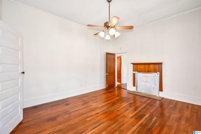 unfurnished living room with ceiling fan, crown molding, and dark wood-type flooring