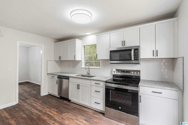 kitchen with light stone countertops, dark hardwood / wood-style flooring, stainless steel appliances, sink, and white cabinets