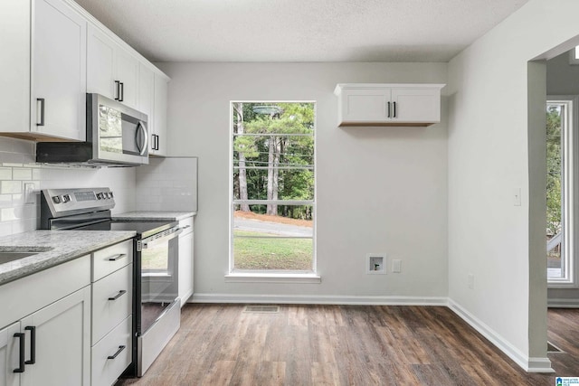 kitchen featuring backsplash, white cabinetry, light stone counters, and appliances with stainless steel finishes