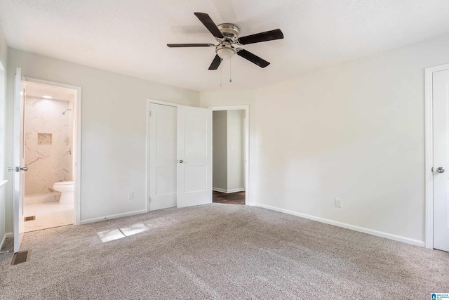 unfurnished bedroom with dark colored carpet, ensuite bath, and ceiling fan