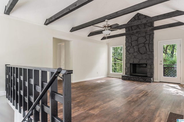 unfurnished living room featuring vaulted ceiling with beams, ceiling fan, a stone fireplace, and a wealth of natural light