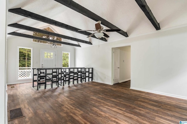 empty room with a textured ceiling, lofted ceiling with beams, dark hardwood / wood-style flooring, and ceiling fan