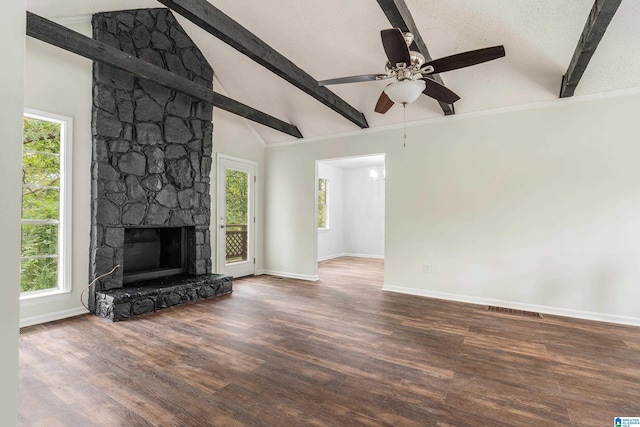 unfurnished living room with a stone fireplace, ceiling fan, a textured ceiling, beam ceiling, and dark hardwood / wood-style flooring