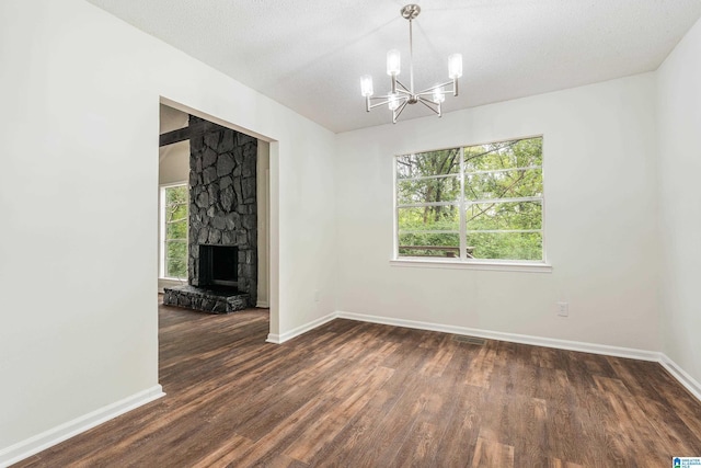 interior space with a textured ceiling, dark hardwood / wood-style flooring, a fireplace, and an inviting chandelier