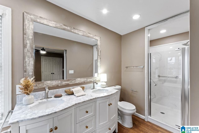 bathroom featuring ceiling fan, toilet, vanity, a shower with shower door, and hardwood / wood-style flooring