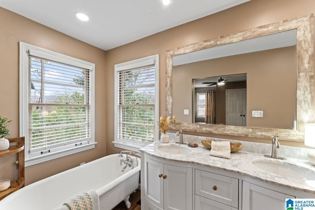 bathroom featuring a wealth of natural light, vanity, a bathtub, and ceiling fan