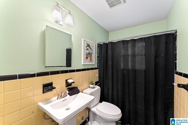 bathroom featuring sink, a shower with shower curtain, tile walls, and toilet