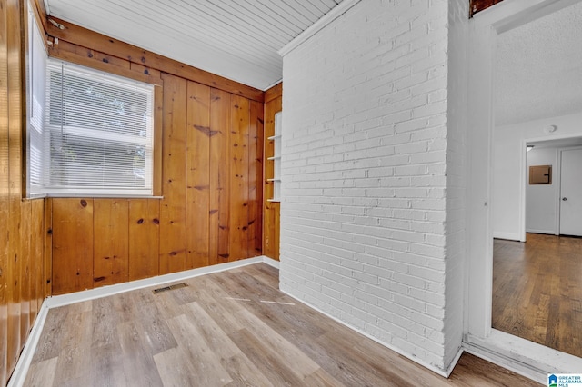 foyer entrance with wooden walls, hardwood / wood-style floors, and brick wall