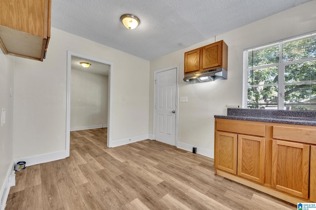 kitchen with light hardwood / wood-style floors, a textured ceiling, and range hood